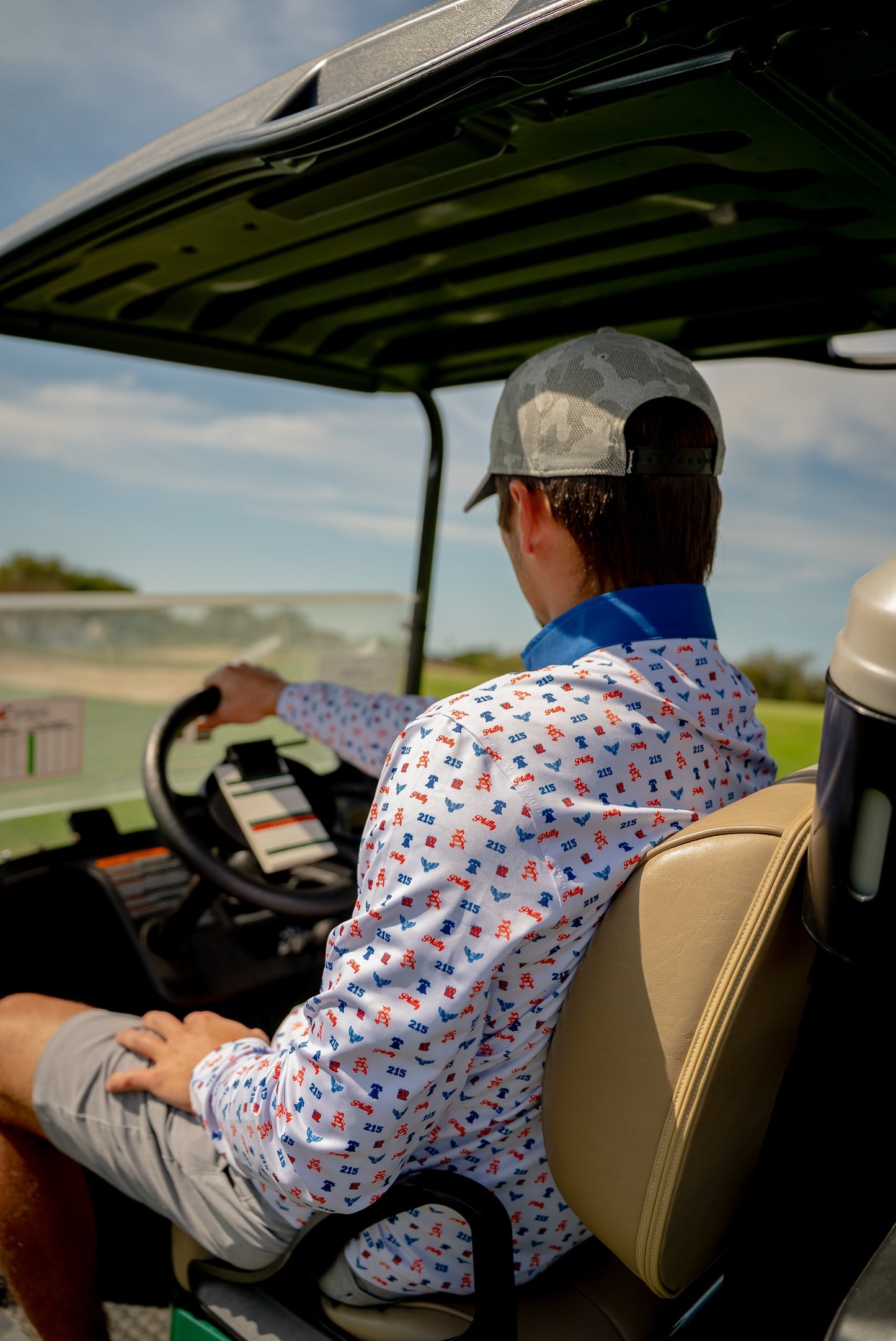 Side view of model wearing the Philly Phrenetic Quarter Zip men’s golf pullover by Foresome Golf Co. while sitting in a golf cart